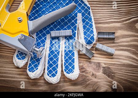 Stapler gun safety gloves staples on wooden board. Stock Photo