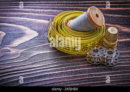 Vintage reel of thread measuring tape thimble spools on wooden board handicraft concept. Stock Photo