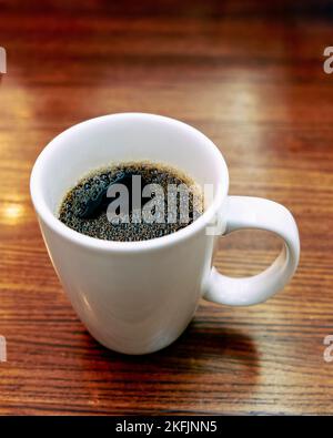 Large white ceramic coffee cup or mug with hot black coffee on a restaurant table. Stock Photo