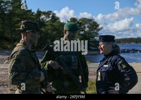 U.S. Marine Corps Capt. Brandon Klewicki (left), and Swedish Marine Capt. Jacob Lindholm (center), joint commanders of the ground force element, greet Swedish Navy Rear Admiral Ewa Skoog Haslum (right), Chief of Swedish Navy, while visiting U.S. and Swedish Marines during exercise Archipelago Endeavor 22 (AE22) on Berga Naval Base, Sweden, Sept. 21, 2022. AE22 is an integrated field training exercise that increases operational capability and enhances strategic cooperation between the U.S. Marines and Swedish forces. Stock Photo