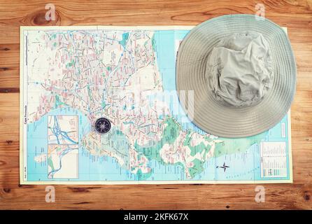 Time to explore. a compass and a hat lying on a map on a table. Stock Photo