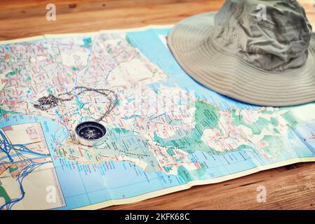 Time to make some discoveries. a compass and a hat lying on a map on a table. Stock Photo