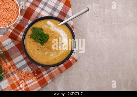 red lentils soup puree in dark bowl with bread on grey marble table Stock Photo