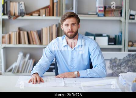Ill give myself 5 stars on this one. Portrait of a handsome young architect sitting at his desk with blueprints in front of him. Stock Photo