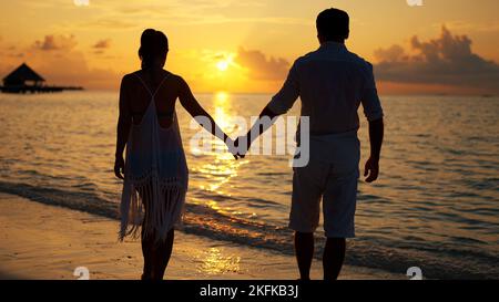 Cropped Image Of Couple Holding Hands At Beach During Sunset Stock Photo