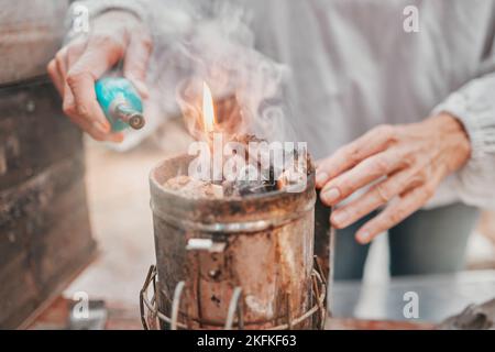 Fire, camping and hands of a senior person start a flame for heating, preparation of food and cooking in nature. Light, heat and woman with a tool for Stock Photo