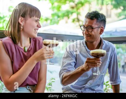 Cute couple flirting and enjoying carefree moment, two young people drinking shaked coffee at restaurant, date between young man and woman created by Stock Photo