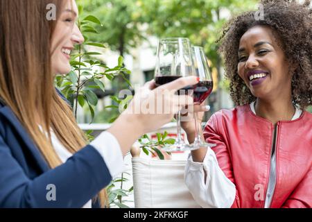 two women toasting with red wine glasses, business people having party for celebrate achievement, friends having fun Stock Photo