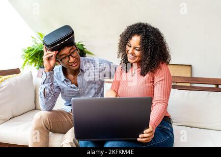 young people of generation z using meta verse reality, biracial woman showing progrss at her friend with vr glasses for augmented reality Stock Photo