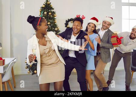 Dancing, running in row, having fun multiracial happy cheerful friends at Christmas party. Stock Photo