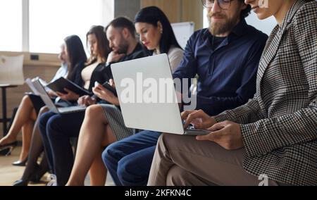 Man and woman working on project and using laptop while sitting in office with other workers Stock Photo