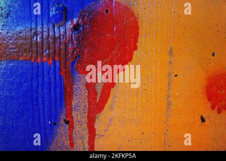 Dripping red paint on a blue and orange concrete wall. Meant as a colorful background Stock Photo