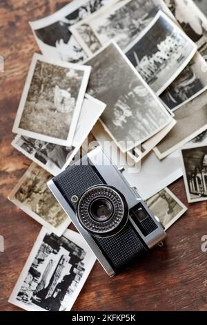 Snapshots from the past. An old-fashioned camera lying on top of a pile of black and white photographs. Stock Photo