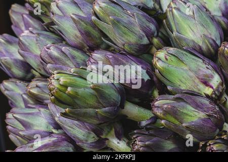 Close up of raw fresh Globe Artichokes on a greengrocers stall at a food market Stock Photo