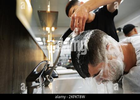 ISTANBUL, TURKEY - MAY 16, 2022: Hairdresser washing hair to his client in barbershop in Esenyurt, Istanbul Stock Photo