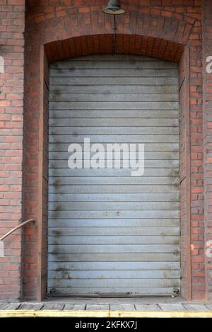 Gray roller door of an old building with a brown brick wall Stock Photo
