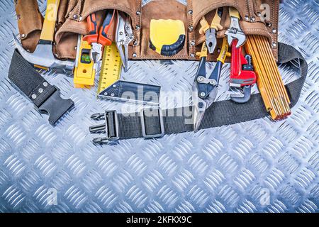 Assortment of construction tooling in leather building belt on channeled metal plate maintenance concept. Stock Photo