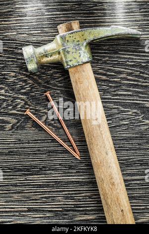 Brass nails claw hammer on wooden board. Stock Photo