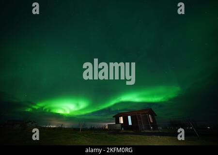 The northern lights, or the aurora borealis, created from a collision between electrically charged particles from the sun that enter the atmosphere of the earth where the particles are redirected by the earth's magnetic field towards the poles, displays over Arabaer near Selfoss on the south coast of Iceland. Picture date: Friday November 18, 2022. Stock Photo