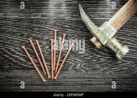 Claw hammer brass nails on wooden board top view. Stock Photo