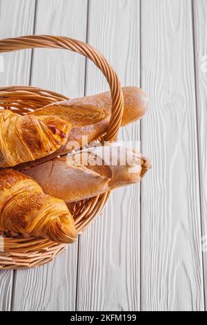 close up view baguettes and croissants in wicker basket on white boards Stock Photo