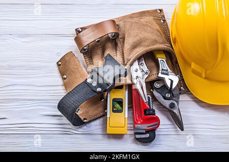 Collection of construction tooling in leather tool belt safety building helmet on wooden board. Stock Photo