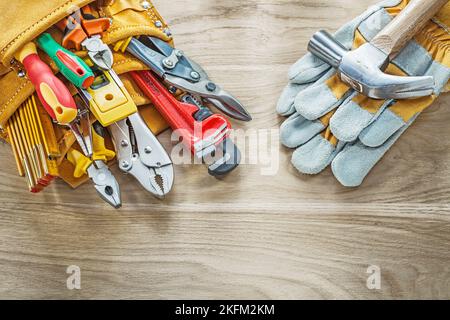Construction tooling tool belt protective gloves on wooden board. Stock Photo