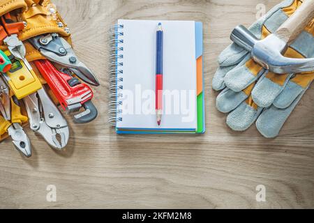 Construction tooling tool belt protective gloves claw hammer notepad pencil. Stock Photo