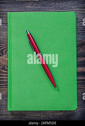 Green notepad ball-point pen on vintage wood board office concept. Stock Photo