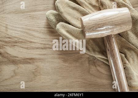 Leather safety gloves lump hammer on wooden board. Stock Photo