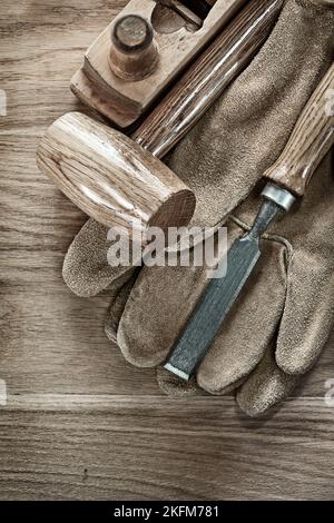 Lump hammer shaving plane chisel protective gloves on wooden board. Stock Photo