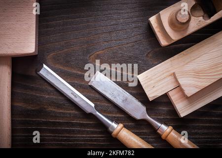 Lump hammer shaving plane flat chisels and wooden bricks on brown vintage board close up view construction concept. Stock Photo