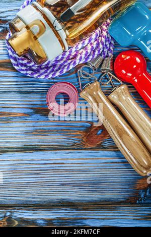 Measuring tape jump rope dumbbells water shaker on wooden board. Stock Photo