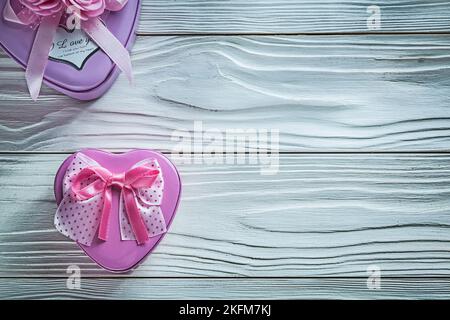 Metal heart-shaped small present boxes on wooden board celebrations concept. Stock Photo