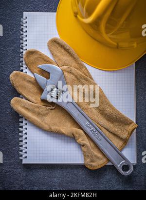 Notebook hard hat adjustable wrench leather working gloves construction concept. Stock Photo
