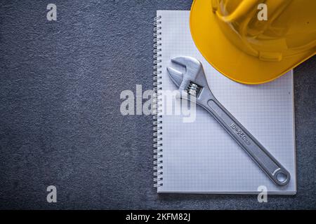 Notebook hard hat adjustable wrench construction concept. Stock Photo