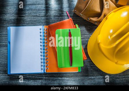 Notebooks pen protective cap leather tool belt on wooden board. Stock Photo