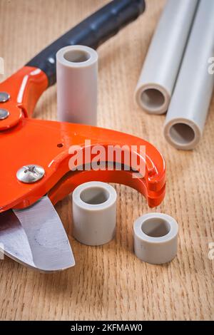 pipe cutter and cutted pipes on wooden board composition Stock Photo