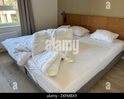 bed, a messy double bed with white bedding sets in a bedroom of a house or home. home interior concept photo with untidy bedroom Stock Photo
