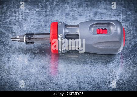Screwdriver with replaceable bits on metallic background construction concept. Stock Photo