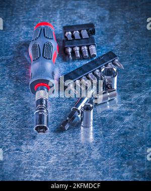 Screwdriver with rubber handle set of replaceable bits and heads on scratched metallic background construction concept. Stock Photo