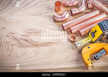 Set of copper water pipe cutter connectors tape line on wooden board plumbing brassware concept. Stock Photo