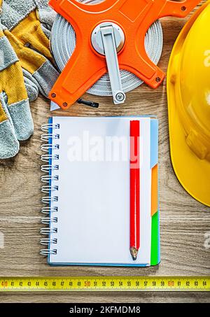 Set of notebook pencil protective gloves measuring tape building helmet on wooden board. Stock Photo
