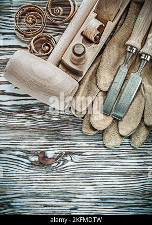 Set of protective gloves wooden hammer chisels planer planning chips. Stock Photo