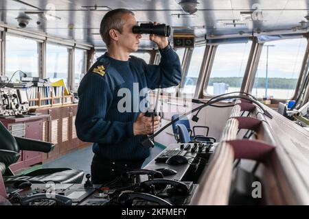 Deck officer with binoculars on navigational bridge. Seaman on board of vessel. Commercial shipping. Cargo ship. Stock Photo