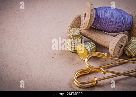 Spools of sewing threads thimbles clasp pins on vintage background. Stock Photo