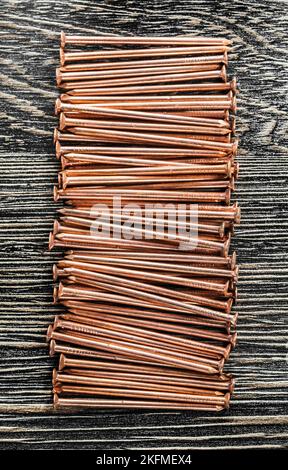 Stack of copper nails on wooden board. Stock Photo