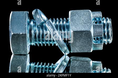 Stainless construction nut screwbolt spring washer on black surface. Stock Photo