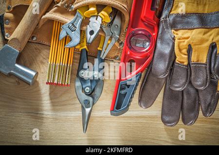 Tool belt with tooling construction level safety gloves on wooden board. Stock Photo