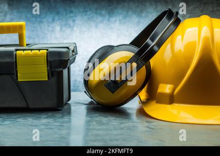 tool box earphones and yellow construction helmet on metalic background Stock Photo